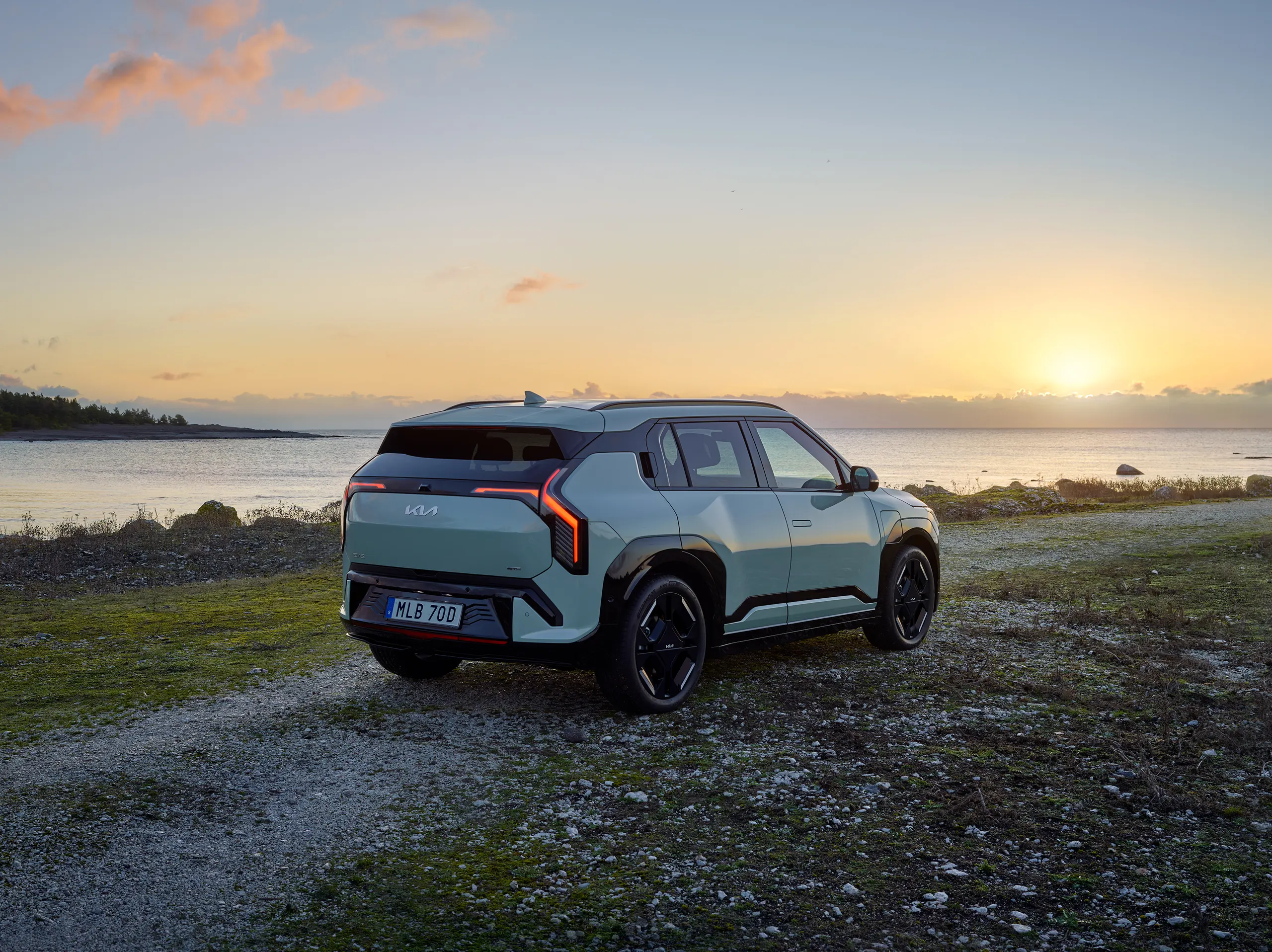 Kia EV3 elbil på en grusväg nära skogskant, optimal för naturutflykter och energieffektiv körning
