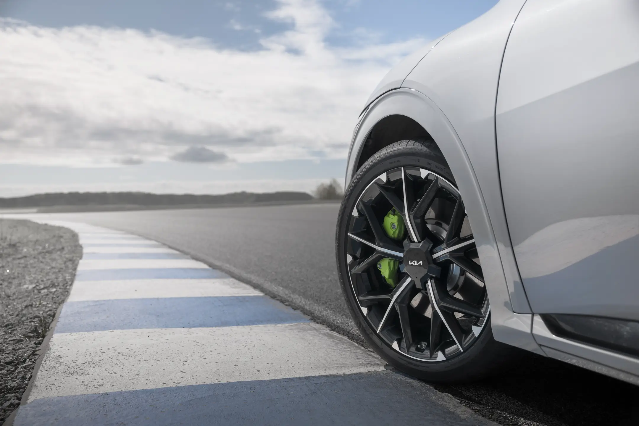 Närbild av Kia EV6 GT:s framhjul med grön bromsok på en grå vägbana