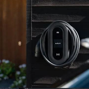 DEFA Power laddbox med Kia-logotyp och laddkabel på en husvägg