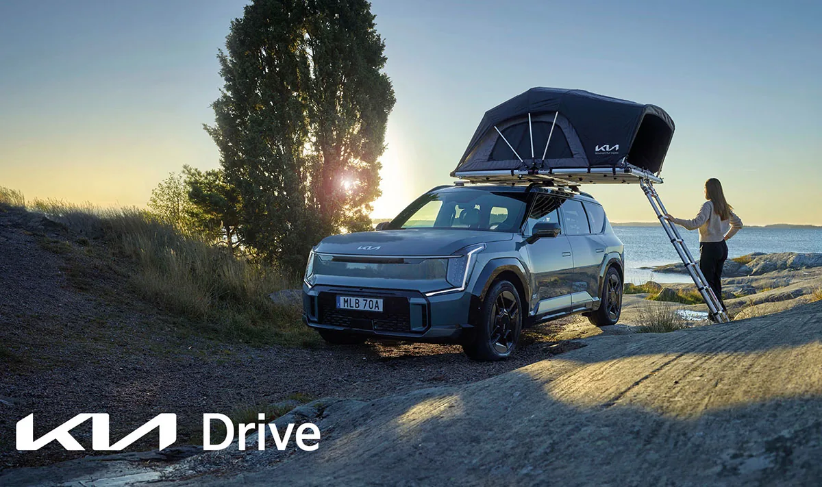Kia EV9 med taktält vid havet och Kia Drive-logotyp