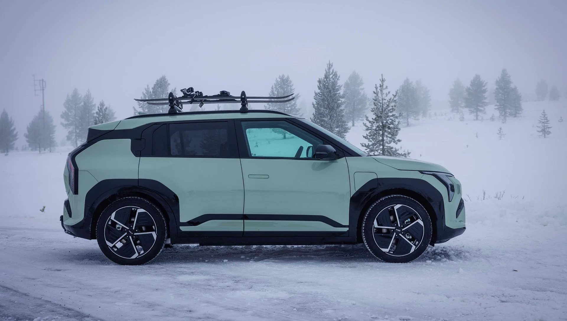 Kia EV3 i profil med skidor på taket i snölandskap hos Bylunds Bil i Karlshamn