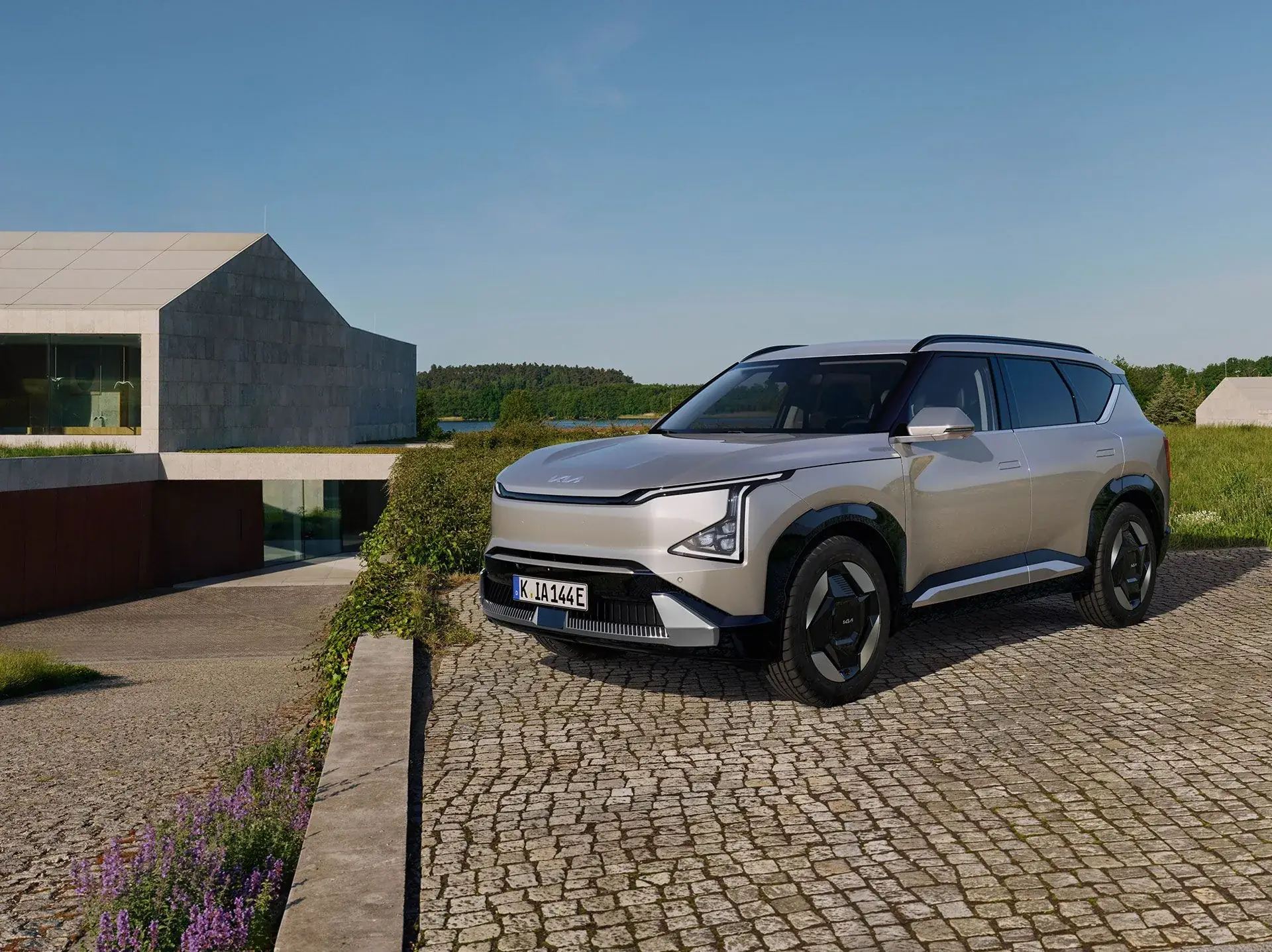 Silverfärgad Kia EV5 snett framifrån på en stenlagd uppfart hos Bylunds Bil i Karlshamn