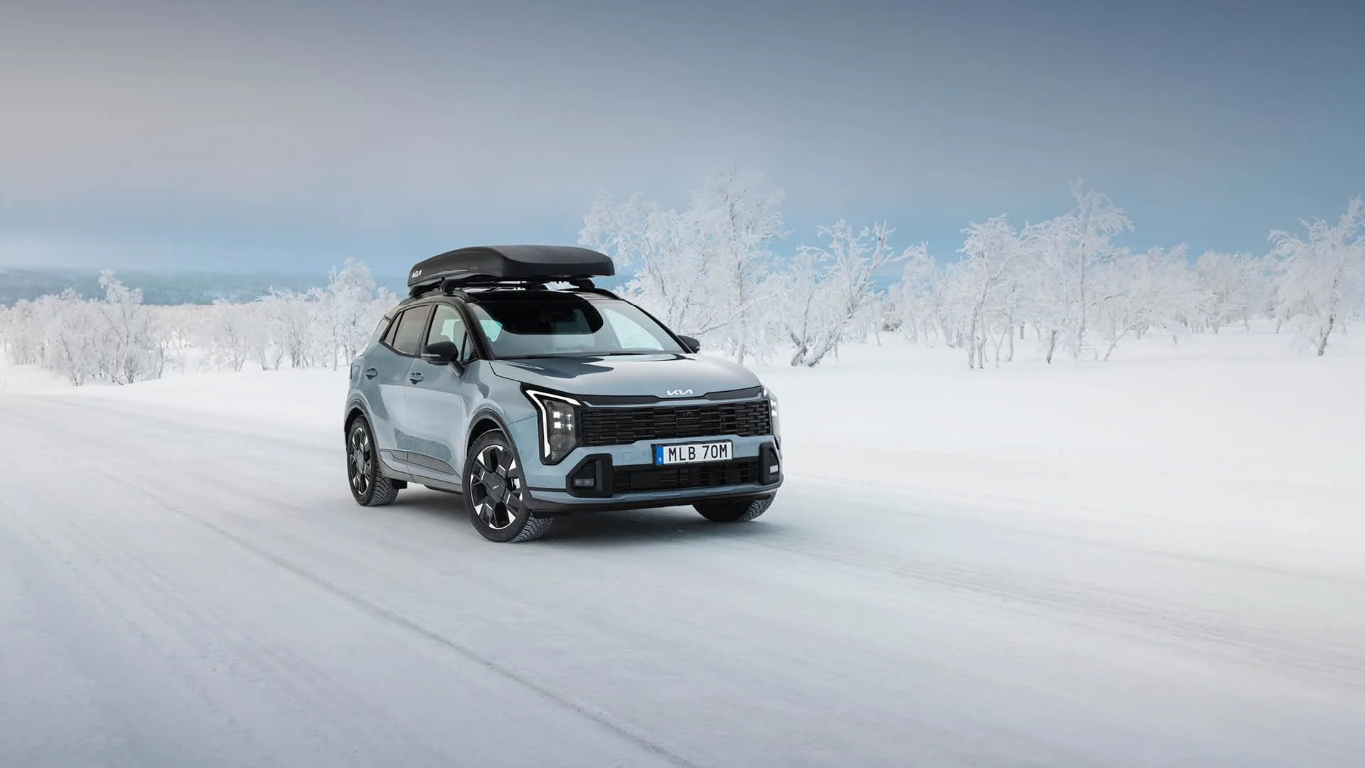 Kia Sportage med takbox framifrån på en snöig väg, hos Bylunds Bil i Karlshamn